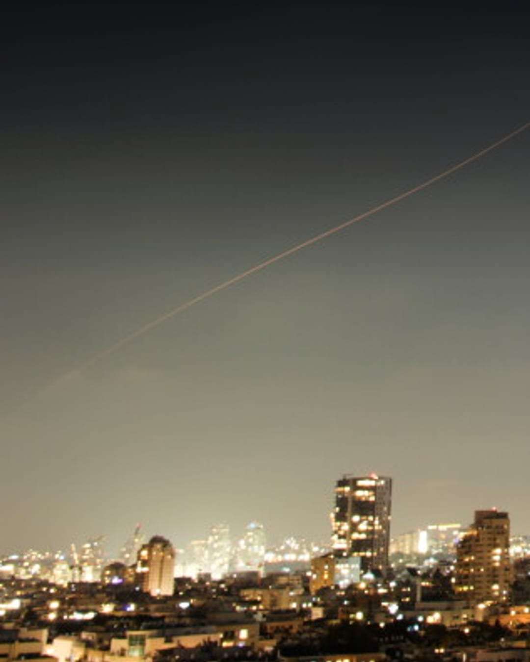 A projectile streaks through the sky over central Israel during an Iranian missile attack