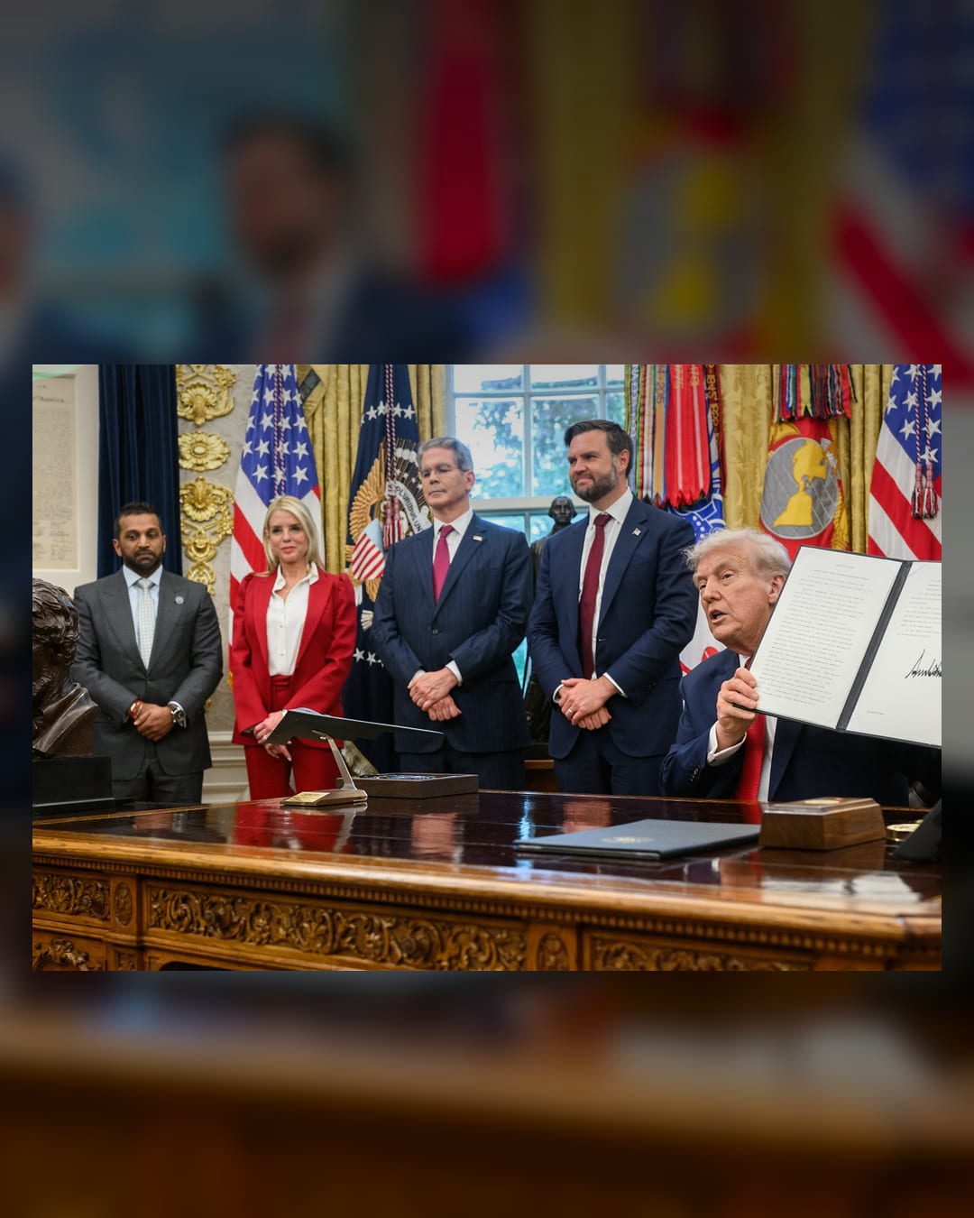 President Donald Trump holds up a signed document in the Oval Office